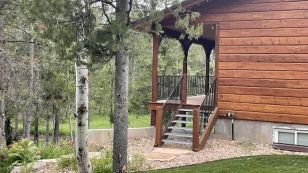 Eine Holzhütte mit überdachter Veranda und einer Treppe zu einer Terrasse.