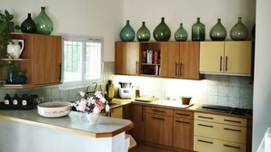 A kitchen with wooden cabinets, a central island, and green vases on the wall.