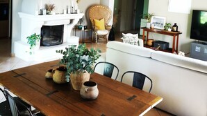 A cozy living room with a fireplace, a dining table with chairs, a sofa, and a television.