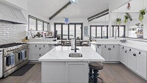 Una cocina moderna con una isla central, electrodomésticos de acero inoxidable y ventanas amplias que ofrecen vistas.