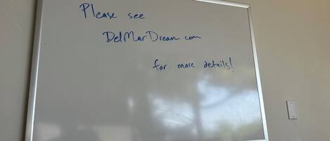 A whiteboard with handwritten text directing to a website for more details.