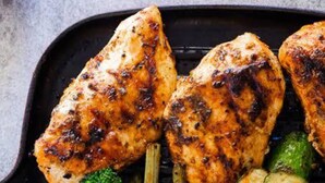 Un piatto con pollo alla griglia, asparagi e verdure.