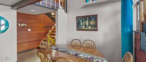 Ein Essbereich mit Holztisch und Stühlen, einer Treppe und einer Wandablage mit Dekoration.