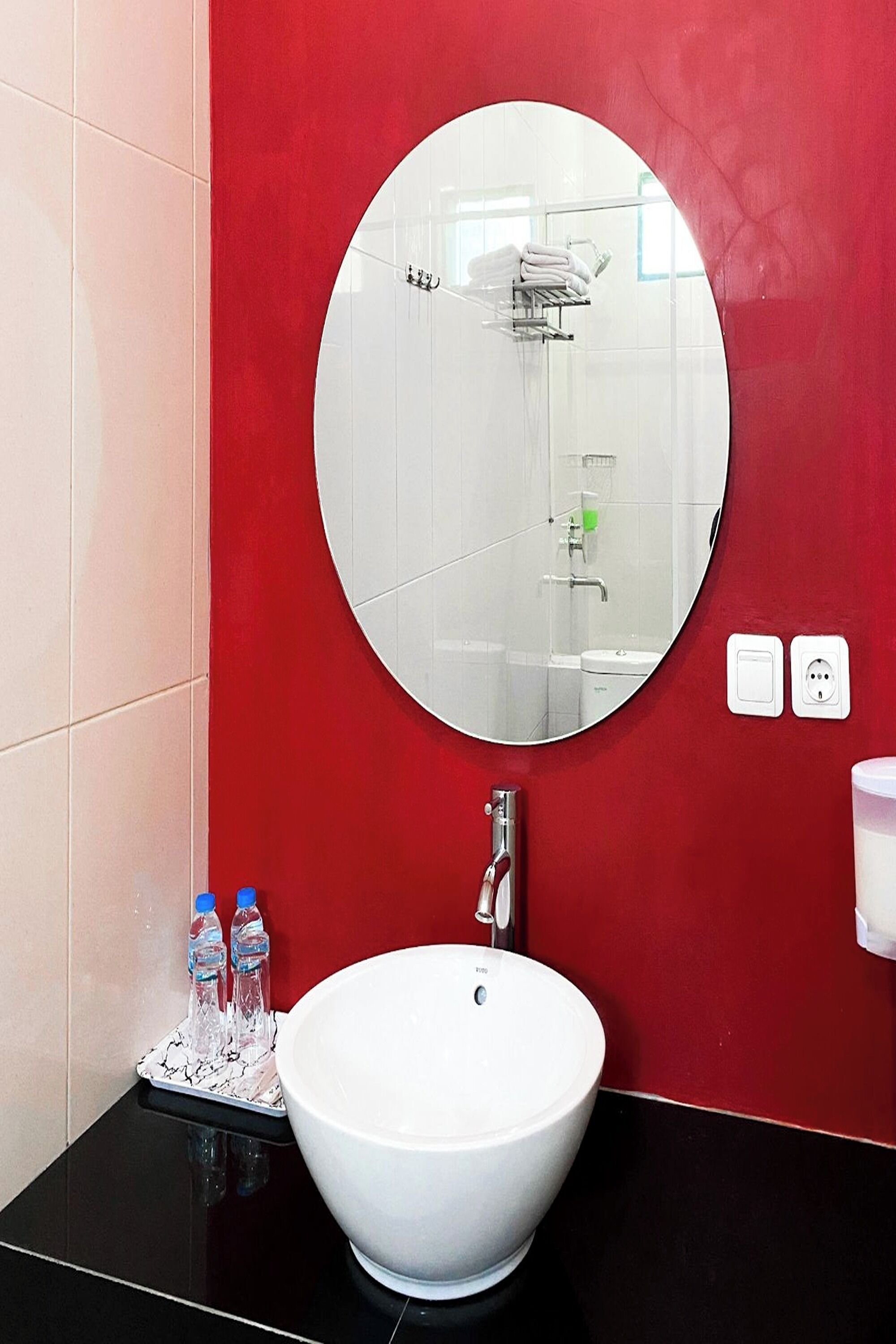A bathroom with a white sink, a round mirror, and red walls.