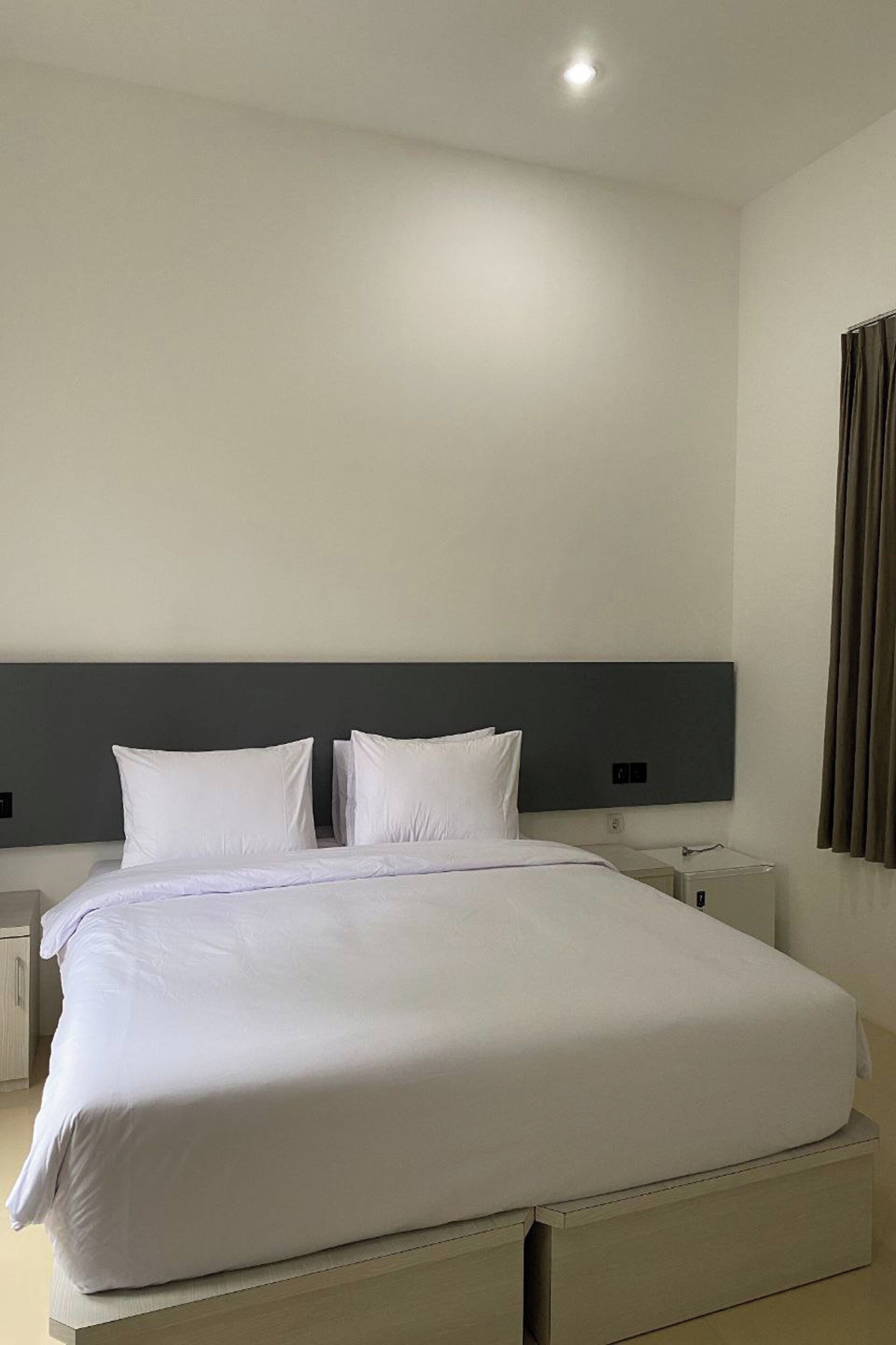 A neatly made bed with white linens in a modern hotel room.