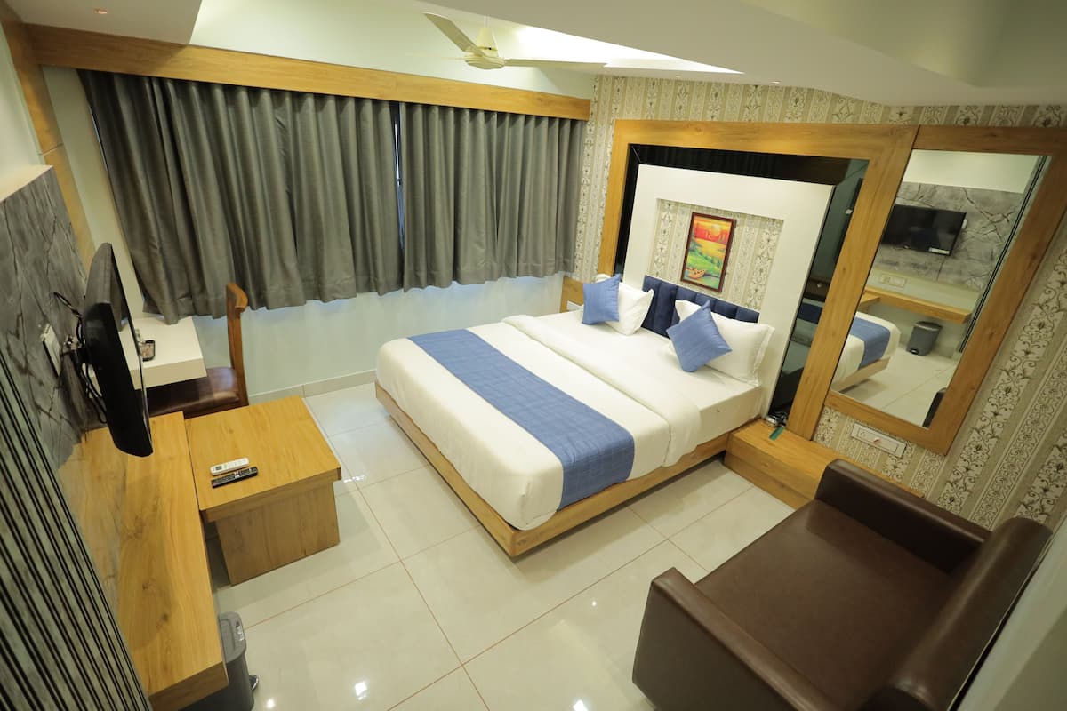 A modern hotel room with a large bed, a wooden desk, a mirror, and a TV.