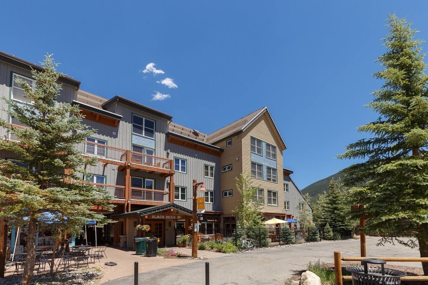 A multi-story hotel with outdoor seating and a mountain backdrop.