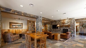A spacious living area with a stone fireplace, wooden furniture, and a stone accent wall. - 8045 Black Bear 1 Bedroom Condo by RedAwning (Keystone)