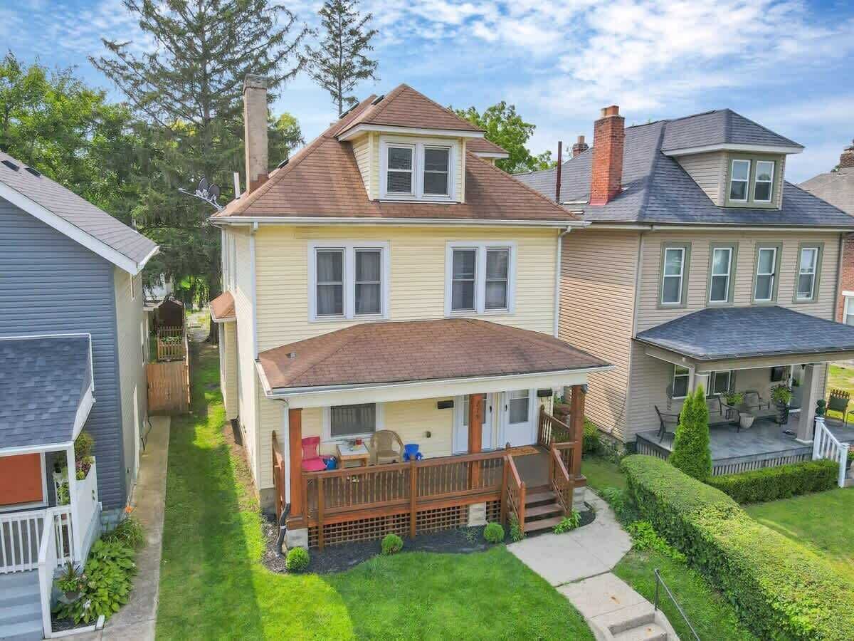 A two-story house with a front porch, a small deck, and a well-maintained lawn.