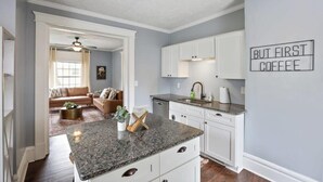 A kitchen with white cabinets, a granite countertop, and a ceiling fan. - The Indiana Stunner S (Columbus)