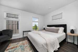 Quarto com cama, mesas de cabeceira, uma cadeira e janela com persianas.