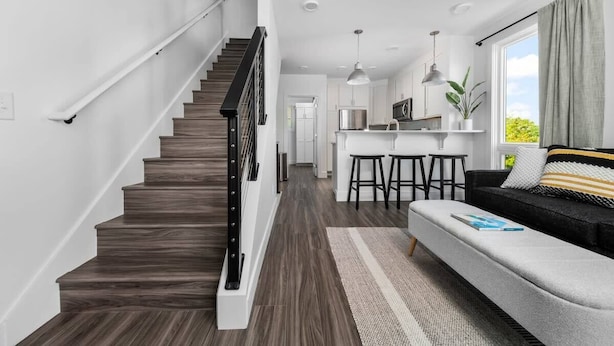 A modern kitchen with white cabinets, a stainless steel refrigerator, and a bar area with stools.