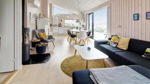 A modern living space with a kitchen, dining area, and a cozy seating area with a sofa and chairs.