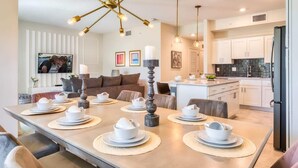 A modern kitchen with white cabinets, a black refrigerator, and a dining area with a wooden table set for four.