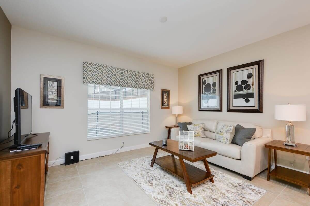 A living room with a sofa, coffee table, TV, and framed artwork.