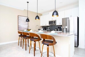 A modern kitchen with white cabinets, stainless steel appliances, and a central island with bar stools.