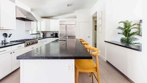 Una cucina moderna con mobili bianchi, un piano di lavoro nero e una penisola centrale con sgabelli da bar.