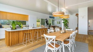 Eine moderne Küche mit einer Holztischinsel, weißen Barhocker und einem Essbereich mit Holztisch und weißen Stühlen.