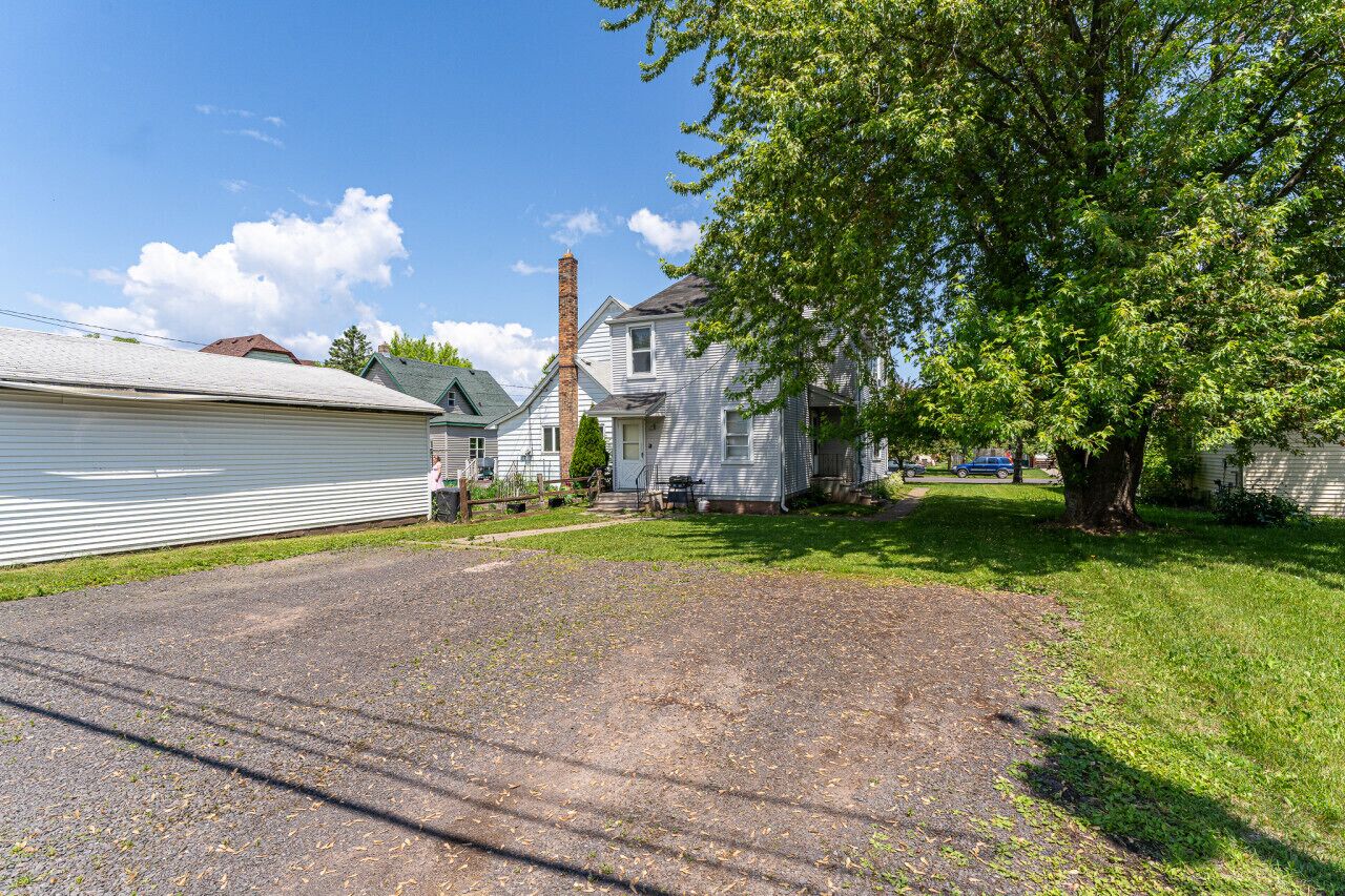 A residential area with a house, a chimney, a tree, and a driveway.