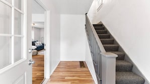 A narrow hallway with a wooden floor and a staircase with grey carpeted steps. - Pattison`s Peaceful Retreat (Superior)