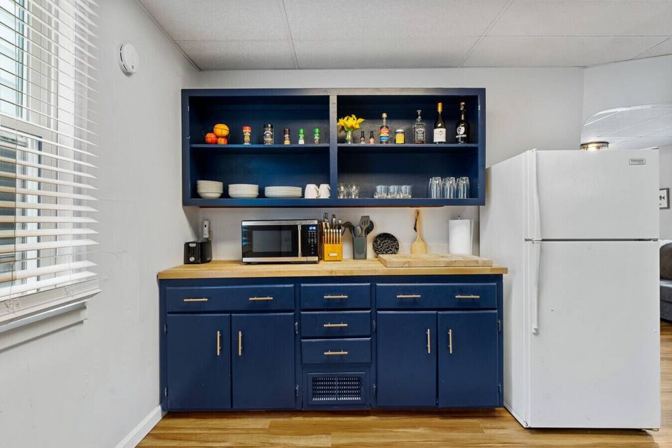 A compact kitchen with dark blue cabinets, a microwave, and a white refrigerator.