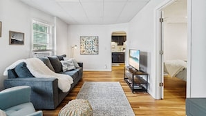 A modern living room with a grey sofa, a TV on a stand, and a wooden floor. - Pattison`s Peaceful Retreat (Superior)