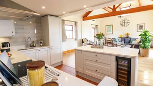 A modern kitchen with white cabinets, a built-in oven, and a central island with a wine cooler. - Rowtor (Matlock)