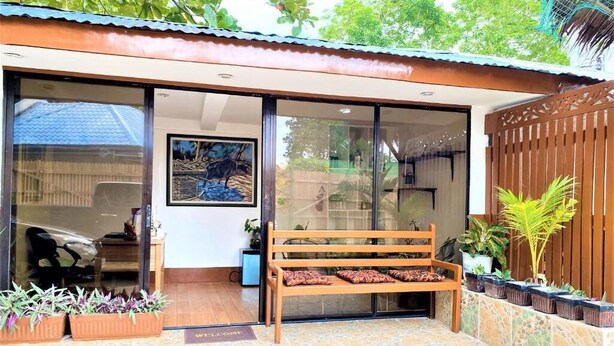 A room with a wooden bench, a sliding glass door, and potted plants. - Villa Tomasa Virgin Hotel (Panglao)