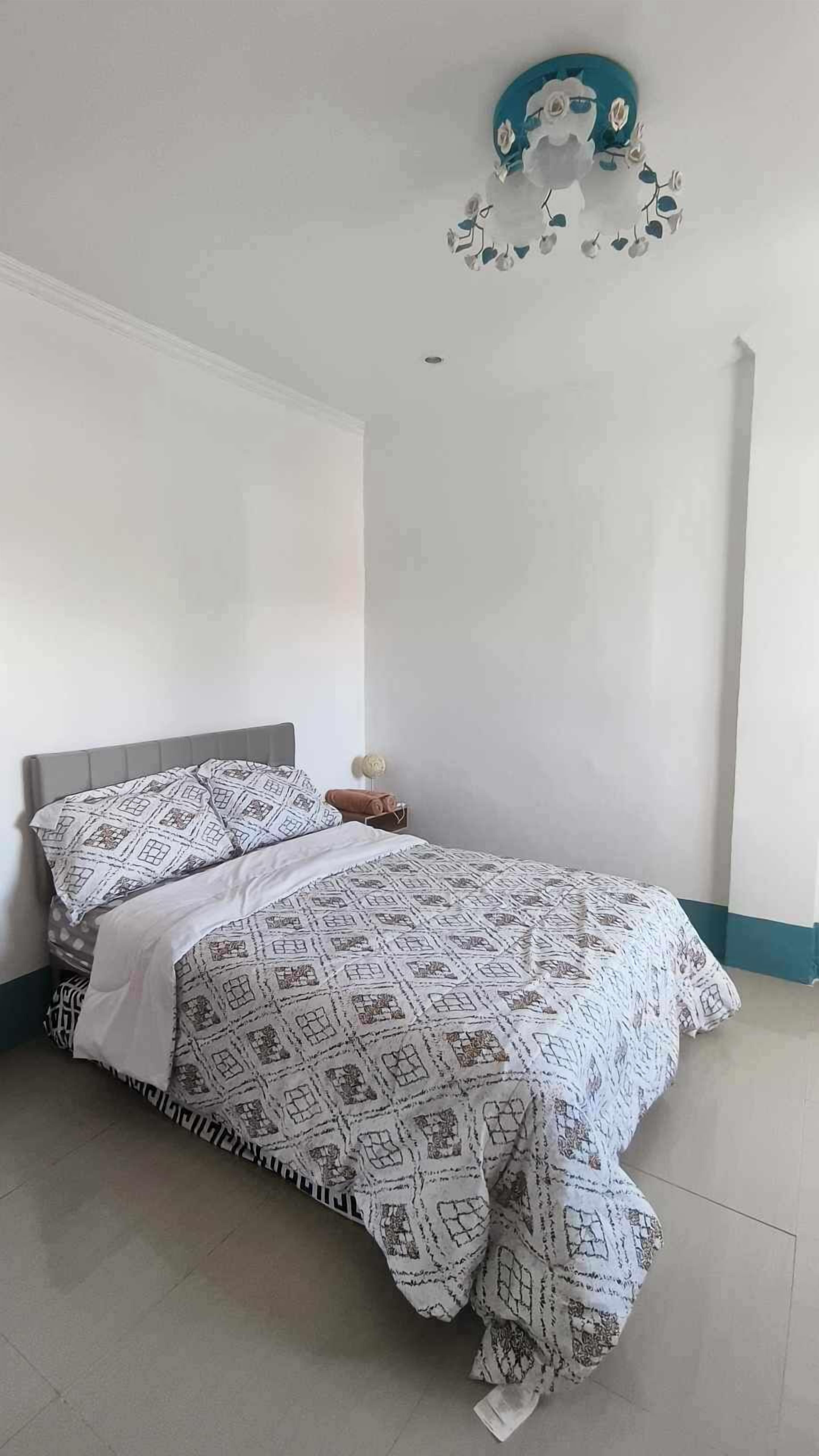 A bedroom with a bed, a nightstand, and a wall decoration.