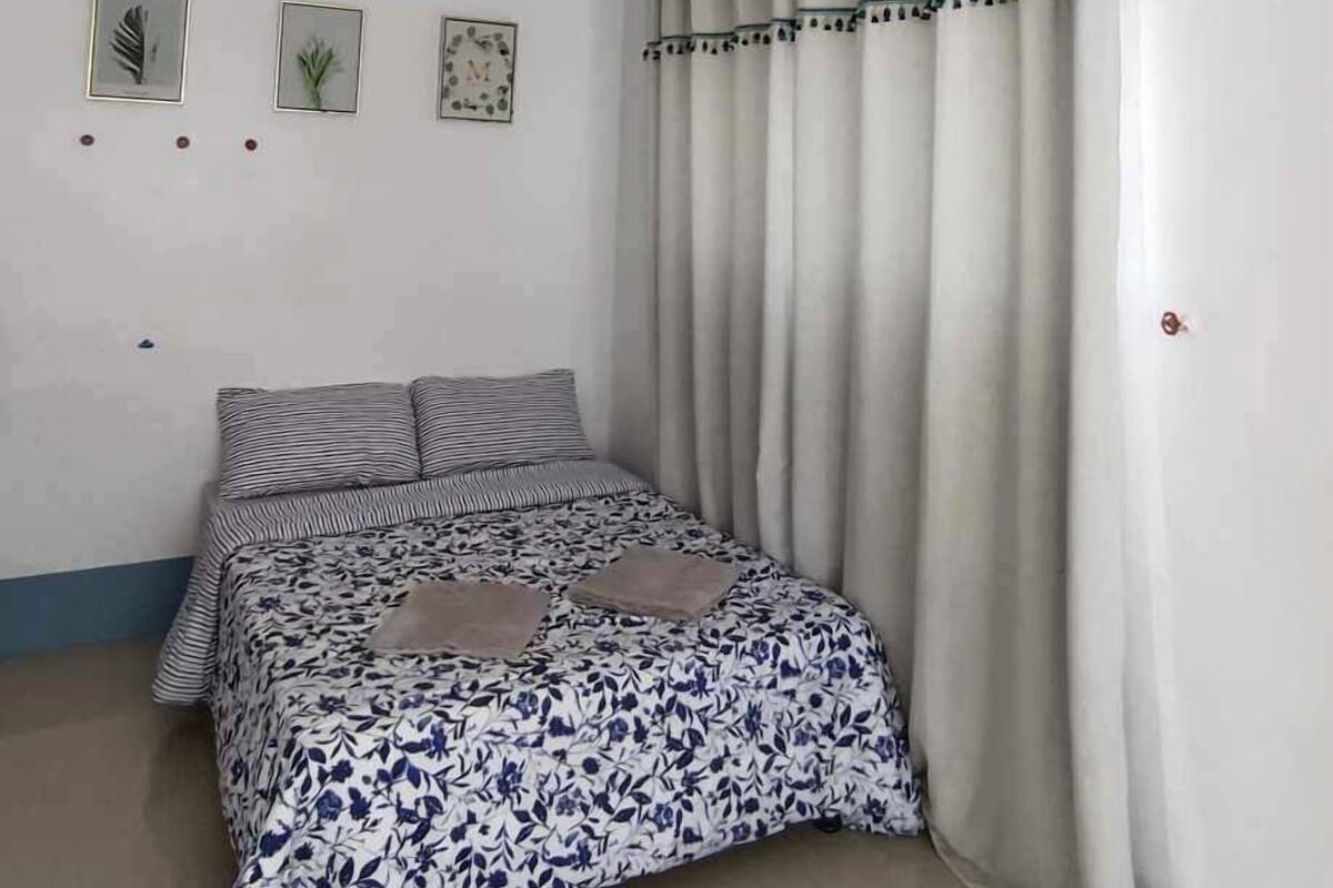 A bedroom with a bed, curtains, and wall art.