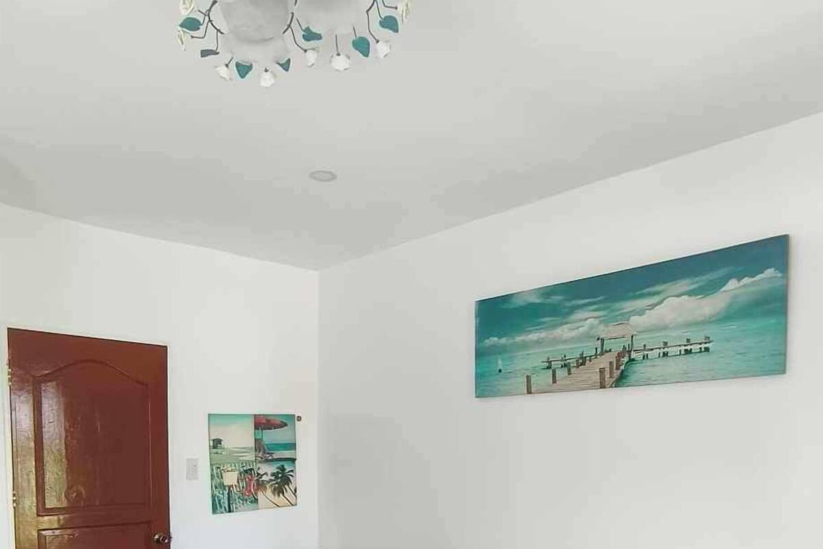 A bedroom with a bed, a painting, a door, and a small table.