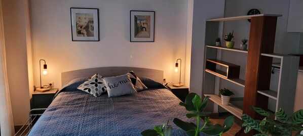 Une chambre à coucher comprenant un lit, deux lampes de chevet, une table de chevet, une bibliothèque et deux tableaux encadrés accrochés au mur.