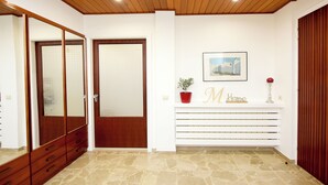 A hallway with a wooden ceiling, a wooden door, a white console table with a potted plant, and a framed picture. - MARTHA'S HOME. Beautiful and comfortable house in Rhodes. (Rodos)
