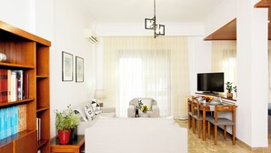A modern living room with a sofa, a dining table with chairs, a TV, and a bookshelf. - MARTHA'S HOME. Beautiful and comfortable house in Rhodes. (Rodos)