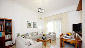 A modern living room with a sofa set, a coffee table, a dining table with chairs, a bookshelf, and a television. - MARTHA'S HOME. Beautiful and comfortable house in Rhodes. (Rodos)