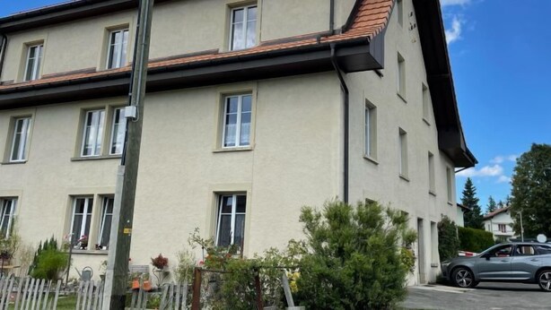A multi-story building with a sloped roof, multiple windows, and a visible satellite dish. - Grand-Rue 143 by Interhome (Sainte-Croix)