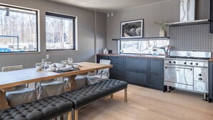 Moderni keittiö, jossa on ruokailutila, suuri ikkuna, liesi ja penkki.