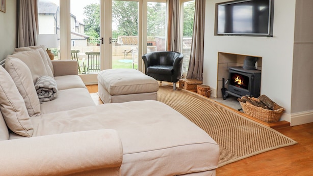 A cozy living room with a sofa, a black chair, a fireplace, and a TV. - Cullernose Cottage (Alnwick)
