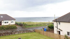 A coastal residential area with houses, a stone wall, and a view of the sea. - Cullernose Cottage (Alnwick)