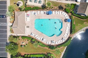 An aerial view of a swimming pool area with lounge chairs and a small deck.