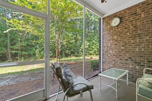 A room with a large window, a brick wall, a clock, and a bench.