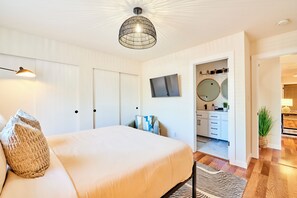A bedroom with a bed, a television, a wardrobe, and a bathroom visible through an open door. - ★ Modern LUX 4 bdrm - Near Mall, Boeing, Paine Field & Eateries! ★ (Everett)