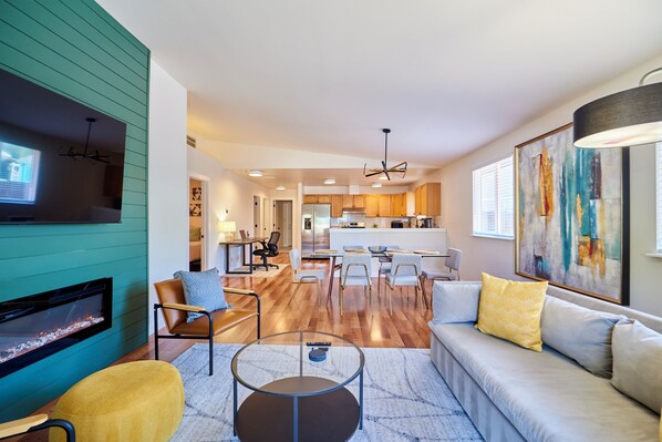 A modern living room with a fireplace, sofa, coffee table, and dining area. - ★ Modern LUX 4 bdrm - Near Mall, Boeing, Paine Field & Eateries! ★ (Everett)