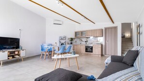 Una sala de estar moderna con sofá, televisión y comedor.