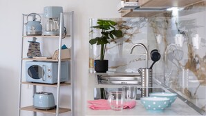 Una cocina con microondas, tostadora, hervidor y una planta en la encimera.