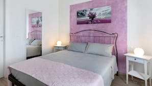 Quarto com cama, mesas de cabeceira, espelho e um quadro na parede.