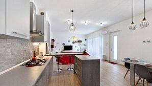 Cozinha moderna com ilha central, banquetas e iluminação pendente.