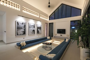Una sala de estar moderna con techo alto, ventanas amplias y un juego de sofá azul.