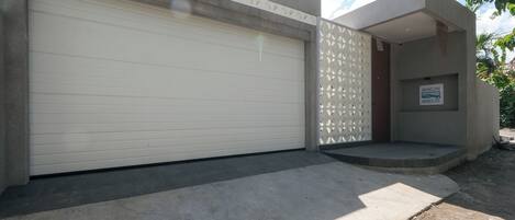 A modern building with a closed garage door, a small entrance with steps, and a sign reading "BINGIN BREEZE".
