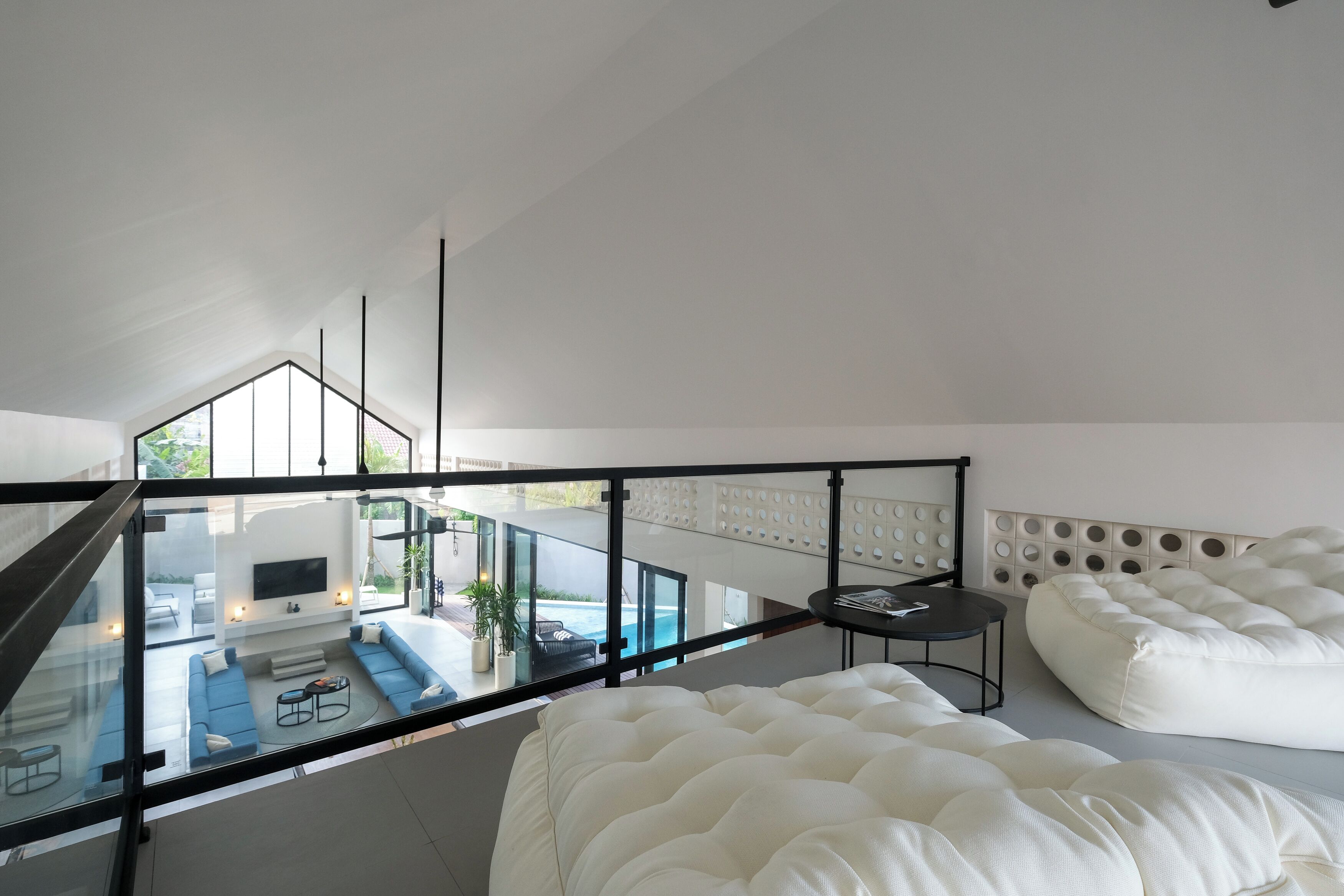 Un dormitorio moderno con balcón de vidrio, una cama grande, un sofá y un televisor.